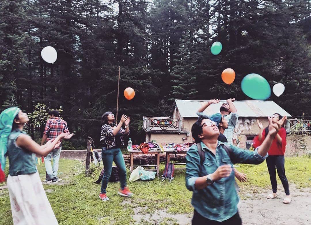 People tossing balloons in a pine forest clearing